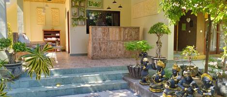 Un intérieur classique avec un comptoir d’accueil, des plantes en pot et des statues.
