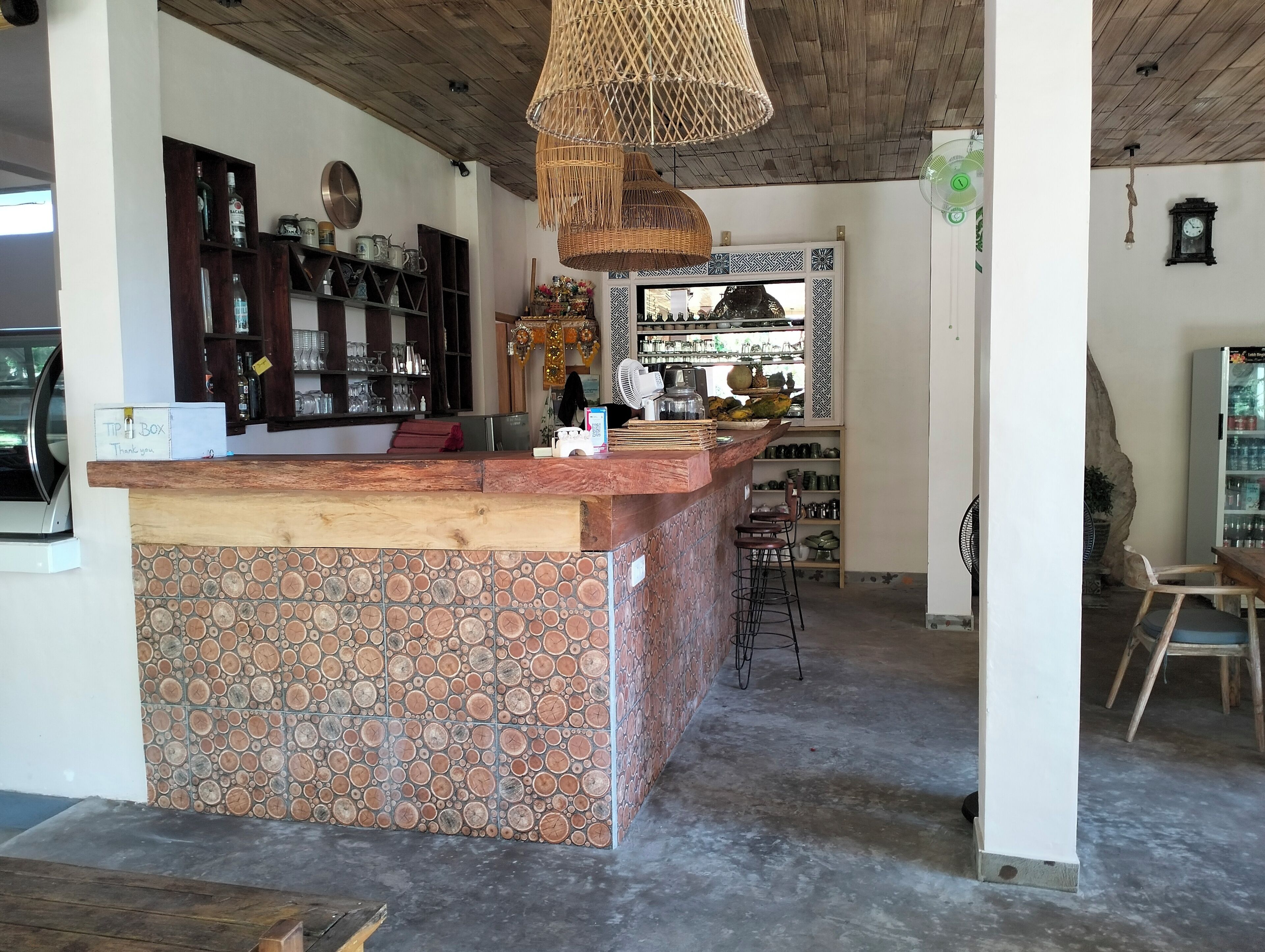A kitchen with a wooden island, a hanging light fixture, and a bar area with shelves and bottles.
