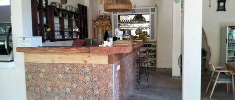 A kitchen with a wooden island, a hanging light fixture, and a bar area with shelves and bottles.