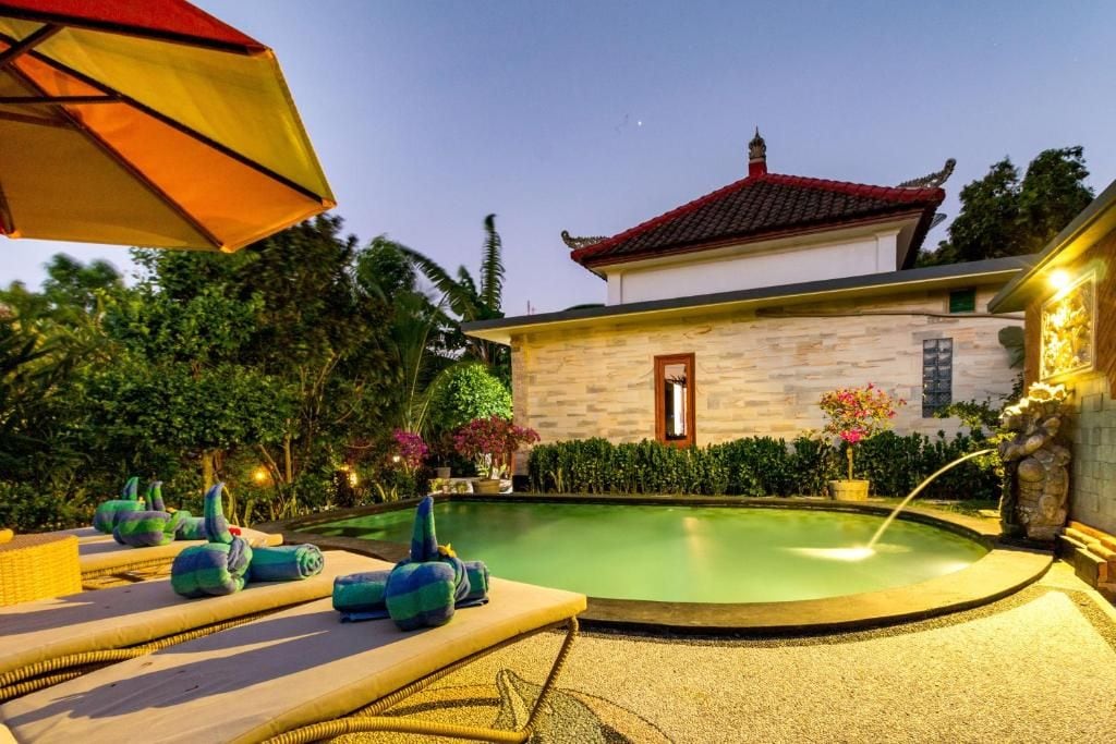 A pool area with lounge chairs and a stone building with a red roof.