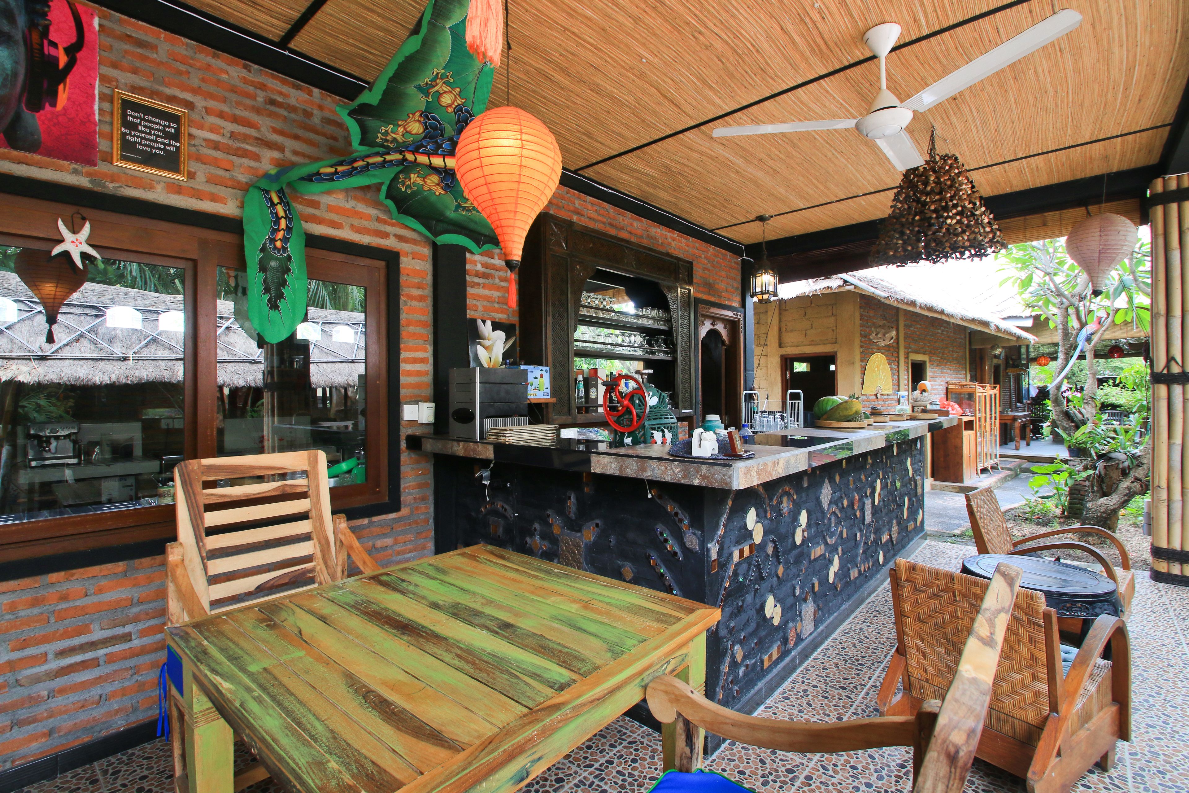 A restaurant with a brick wall, wooden furniture, and a thatched roof.