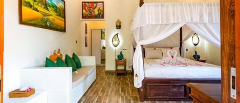 A bedroom with a canopy bed, a sofa, and a painting on the wall.