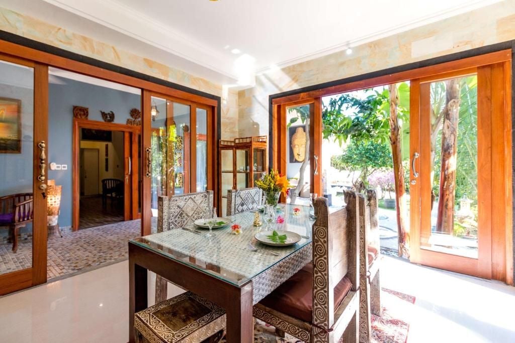 Un comedor con mesa de vidrio, sillas estampadas y vistas al exterior.