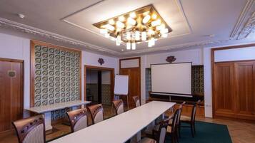 A conference room with a long table, chairs, a projector screen, and a whiteboard.