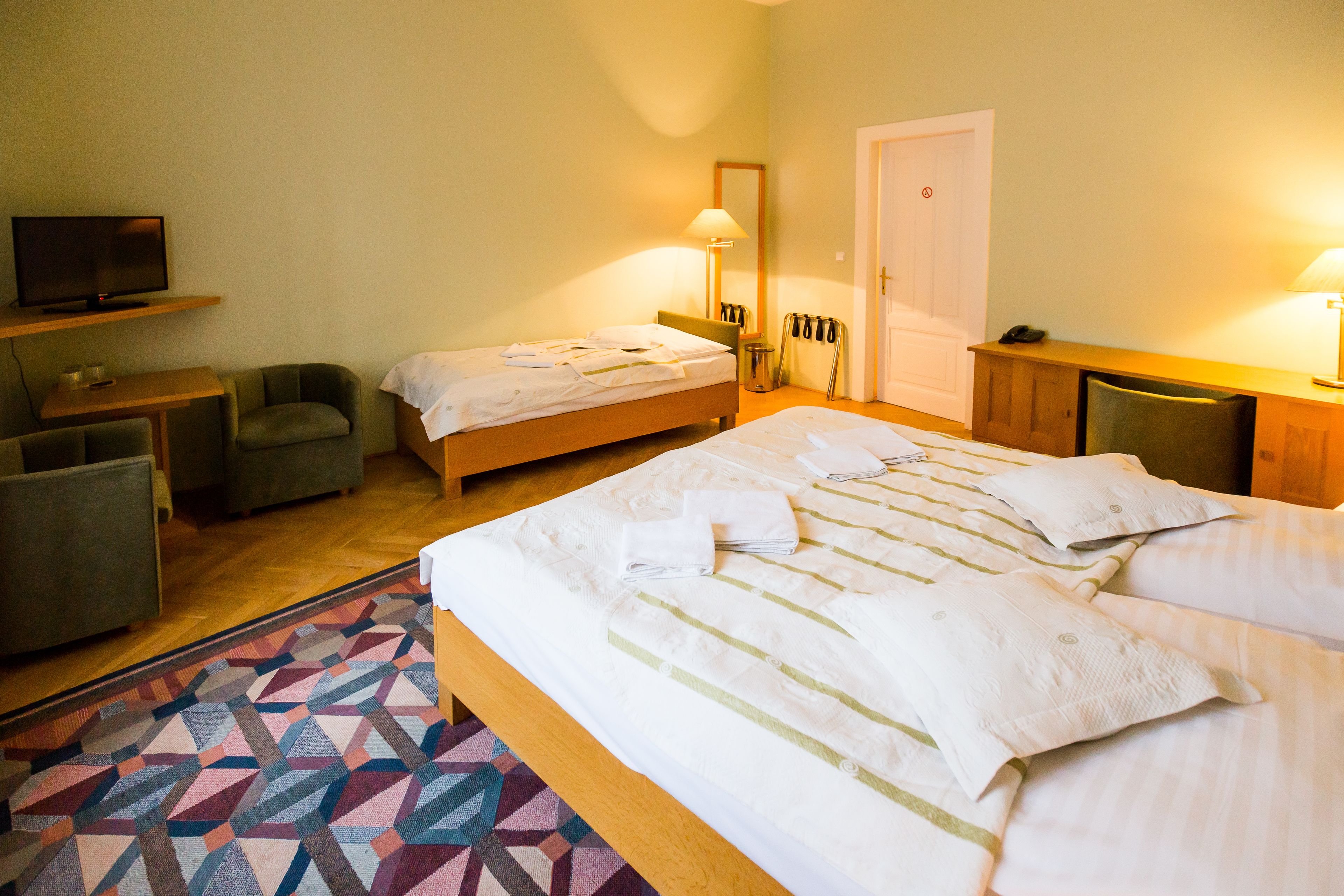 Una camera d'albergo con un letto, una televisione, una scrivania e una sedia.