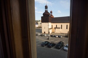 A view through a window of a parking lot with several cars, a building with domed roofs, and a clear sky.