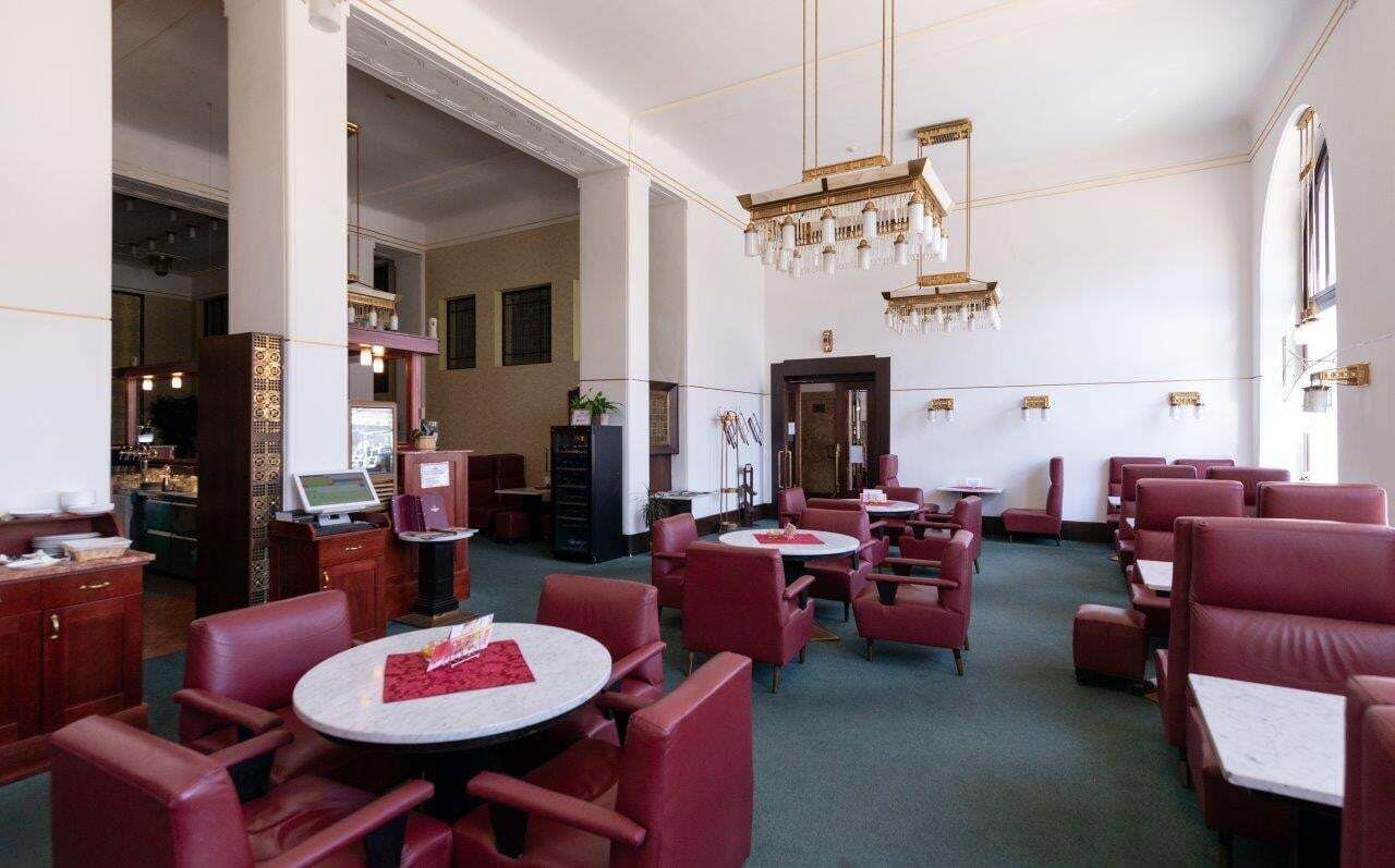 A hotel lobby with red upholstered seating, a chandelier, and a reception area with a computer monitor.