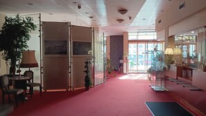 A hotel lobby with a red carpet, glass partitions, and potted plants. - Hotel U Beránka (Nachod)