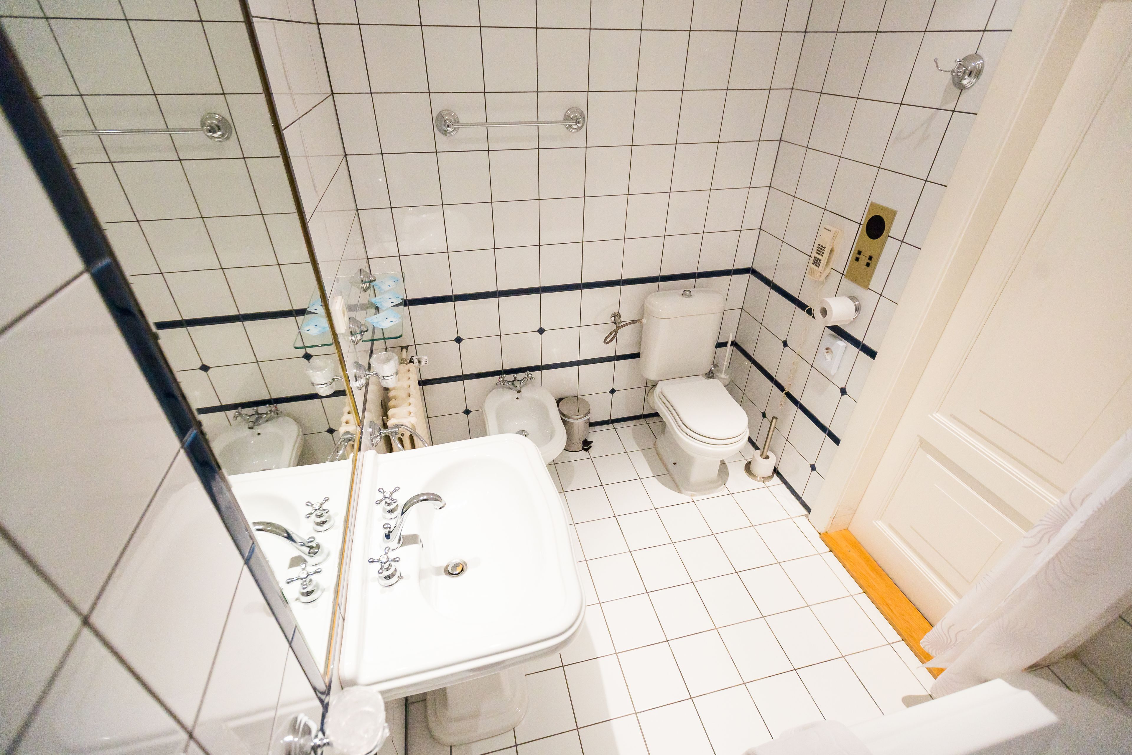 Ein kleines, sauberes Badezimmer mit weißen Fliesen, einem Waschbecken, einer Toilette und einem Bidet.