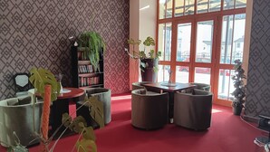 A cozy lobby with a red carpet, a bookshelf, and a seating area with cushioned chairs. - Hotel U Beránka (Nachod)