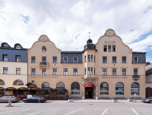 A historic building with a central entrance, multiple balconies, and a prominent dome.