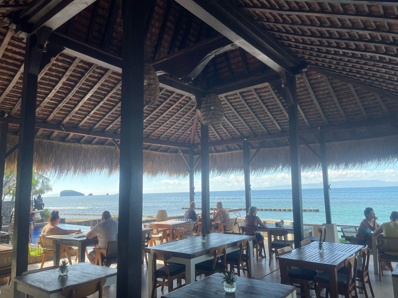 Un área de estar al aire libre con mesas y sillas, con vista al mar.