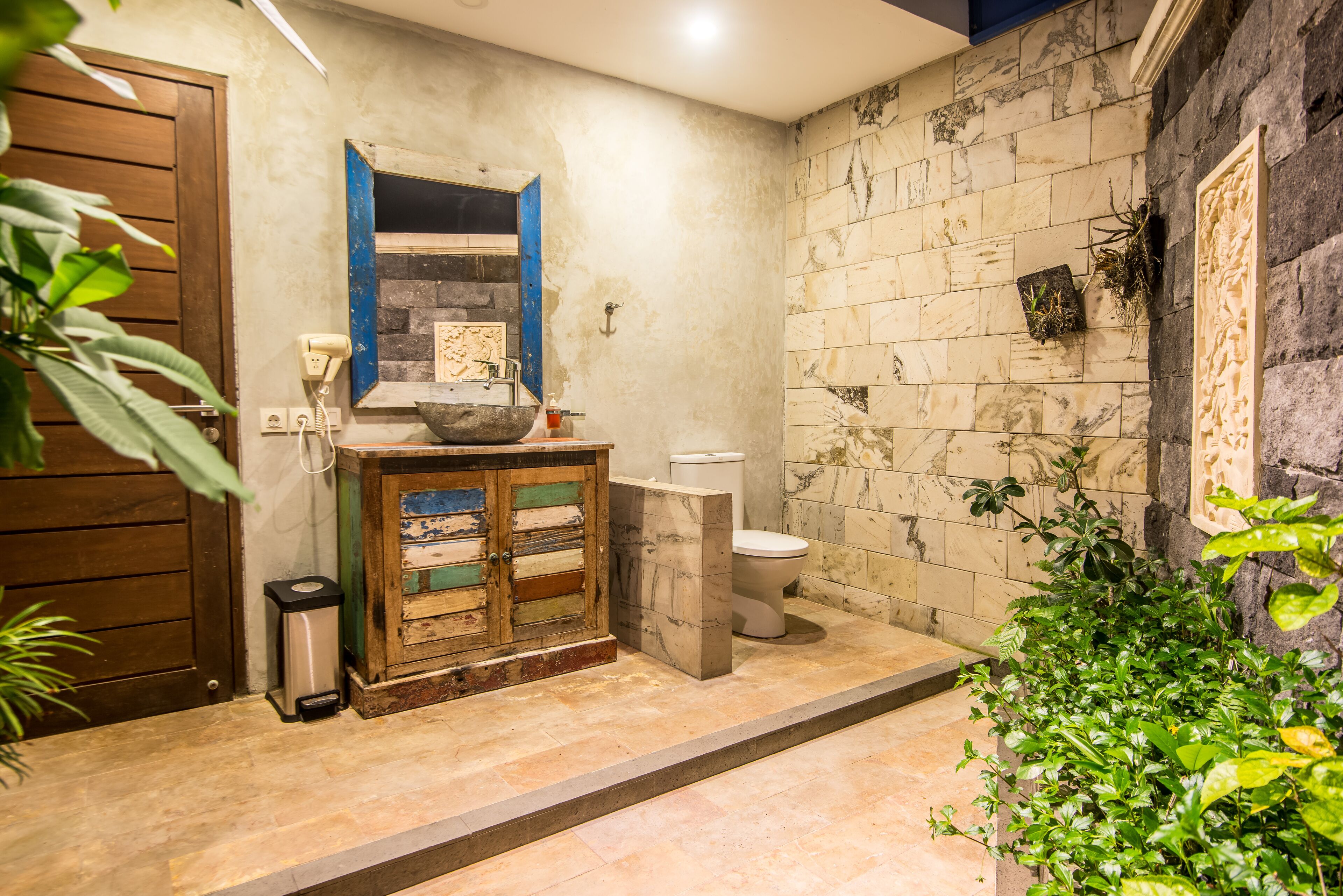 Une salle de bain comprenant des toilettes, un lavabo avec un plan de toilette en marbre et un meuble en bois.