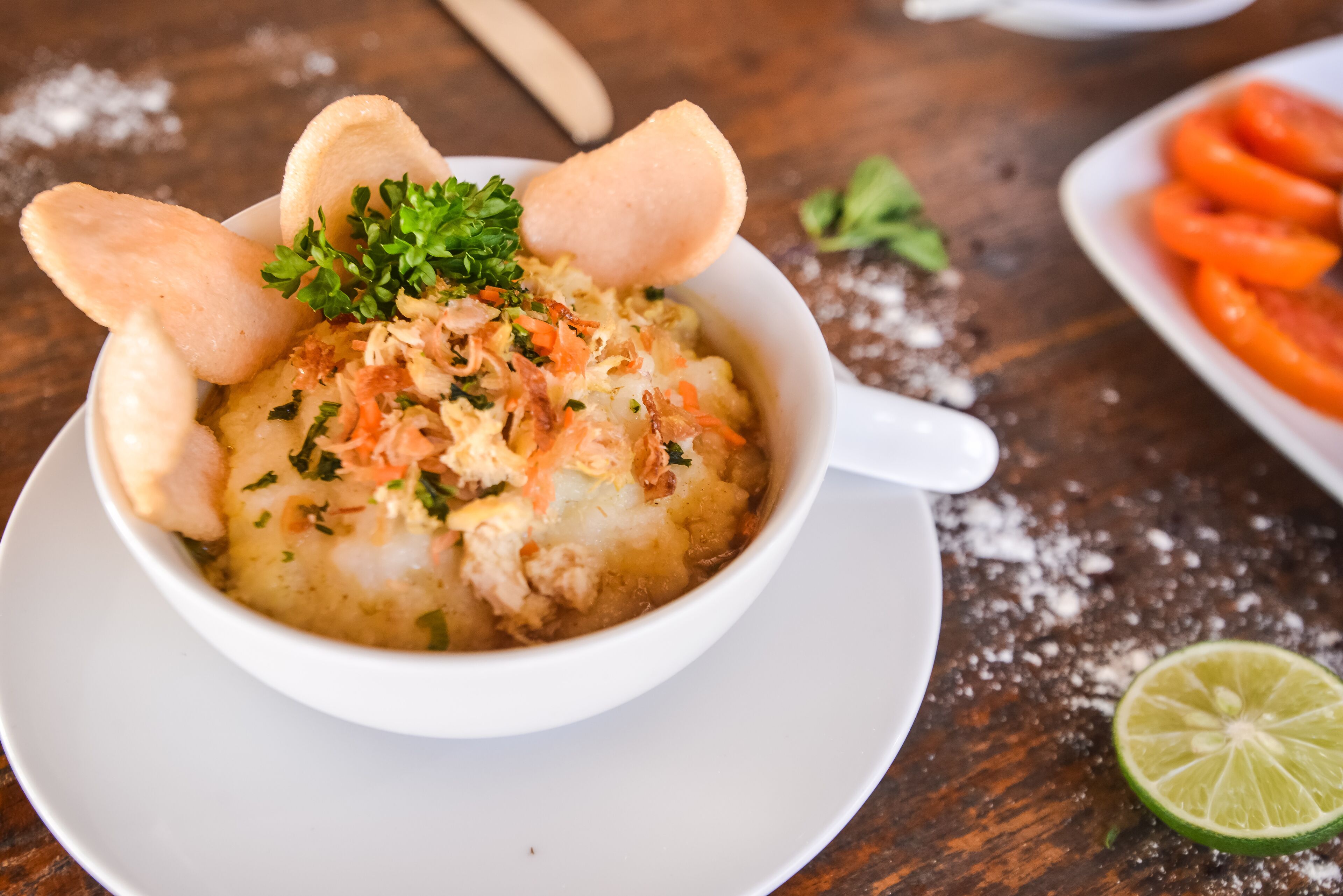 A bowl of food with breadsticks and parsley garnish on a wooden table.