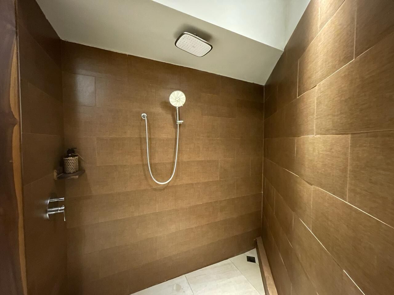 A small, modern shower room with a single showerhead and a handheld shower attachment.