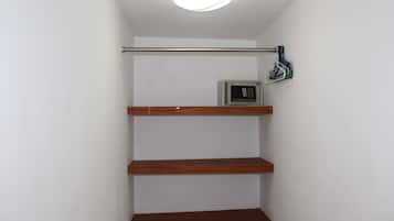 A corner of a room with a white wall, a wooden shelf, and a ceiling light.