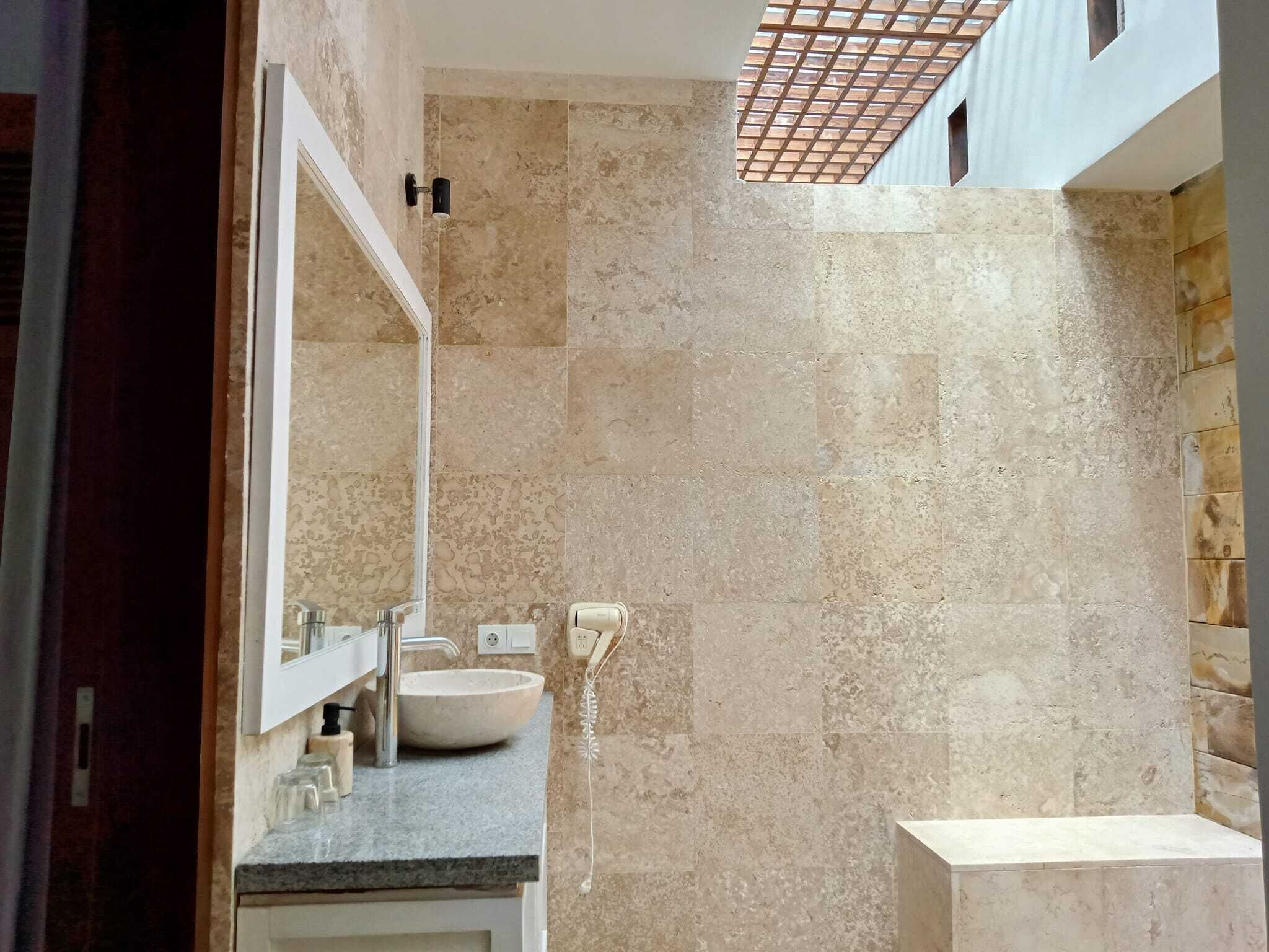 Un baño con un espejo grande, un lavamanos y una zona de ducha.