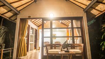 Una habitación con techo de paja, muebles de madera y vistas a través de un ventanal.