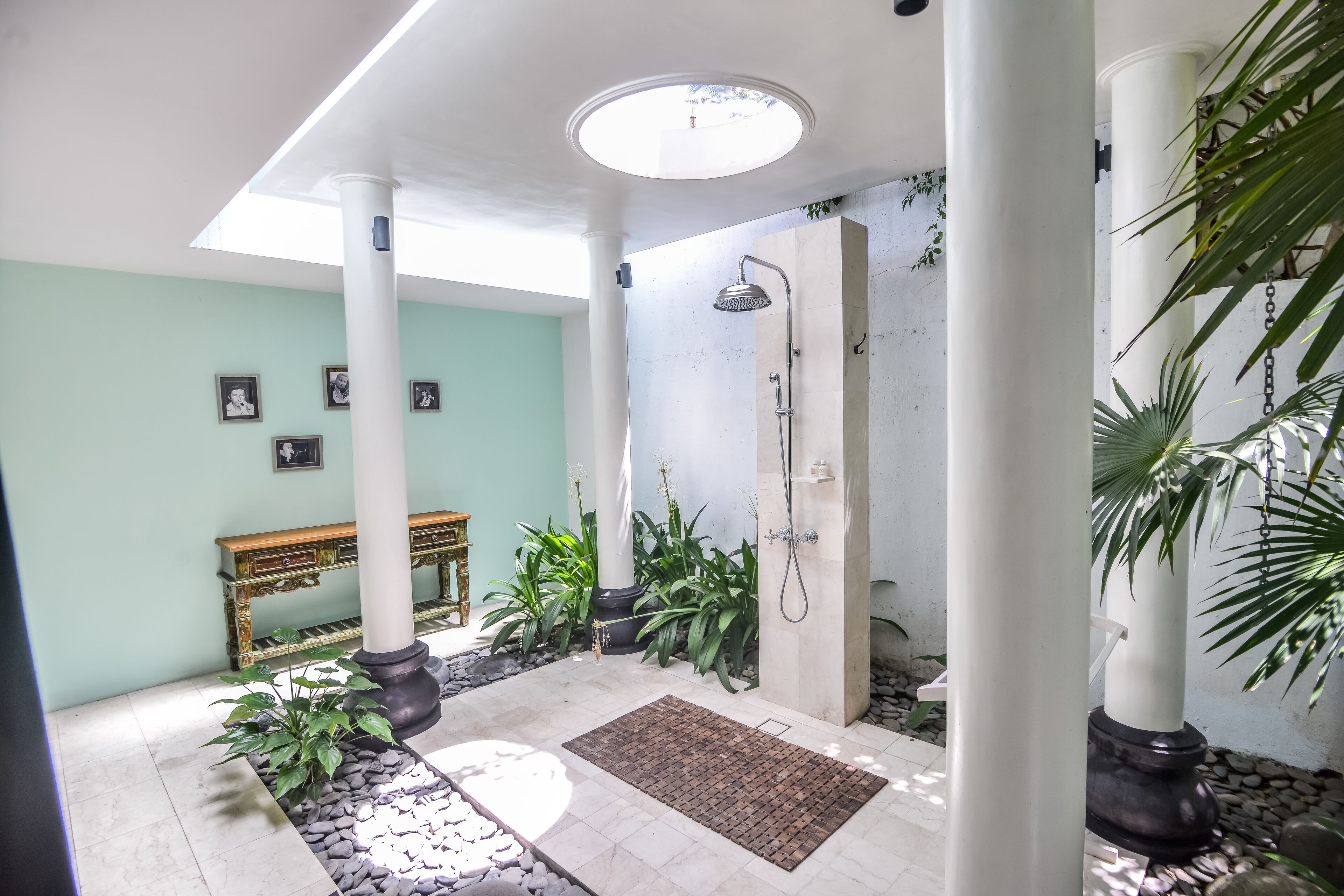 A spacious indoor area with a shower, potted plants, and a bench.