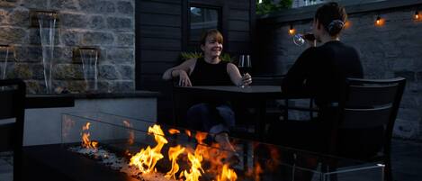 An outdoor seating area with a fire feature, stone wall, and a window.