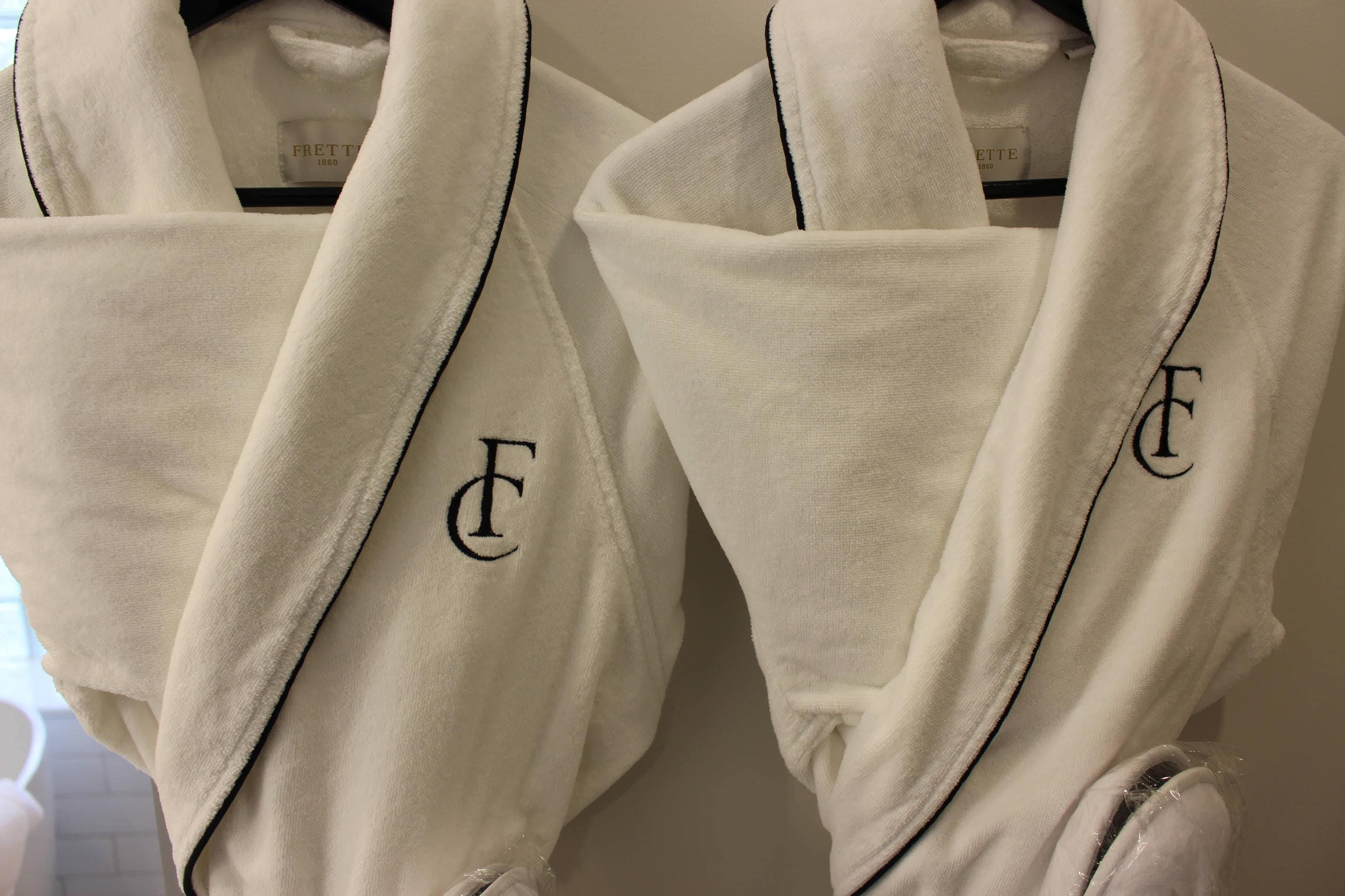 Two white robes with black lettering hanging on a rack.
