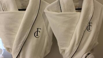 Two white robes with black lettering hanging on a rack.