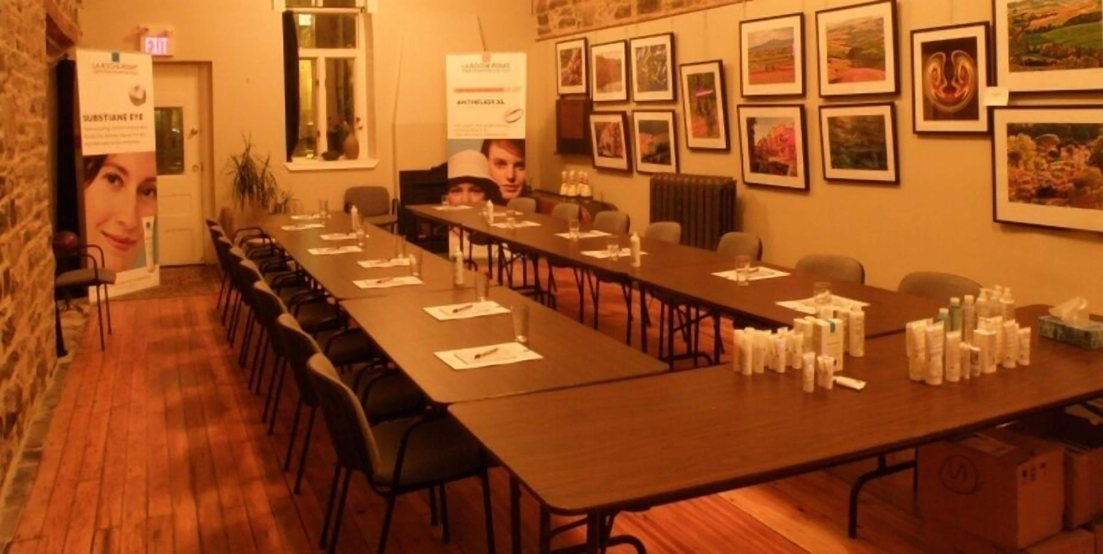 A conference room with long tables, chairs, and various items on the tables.