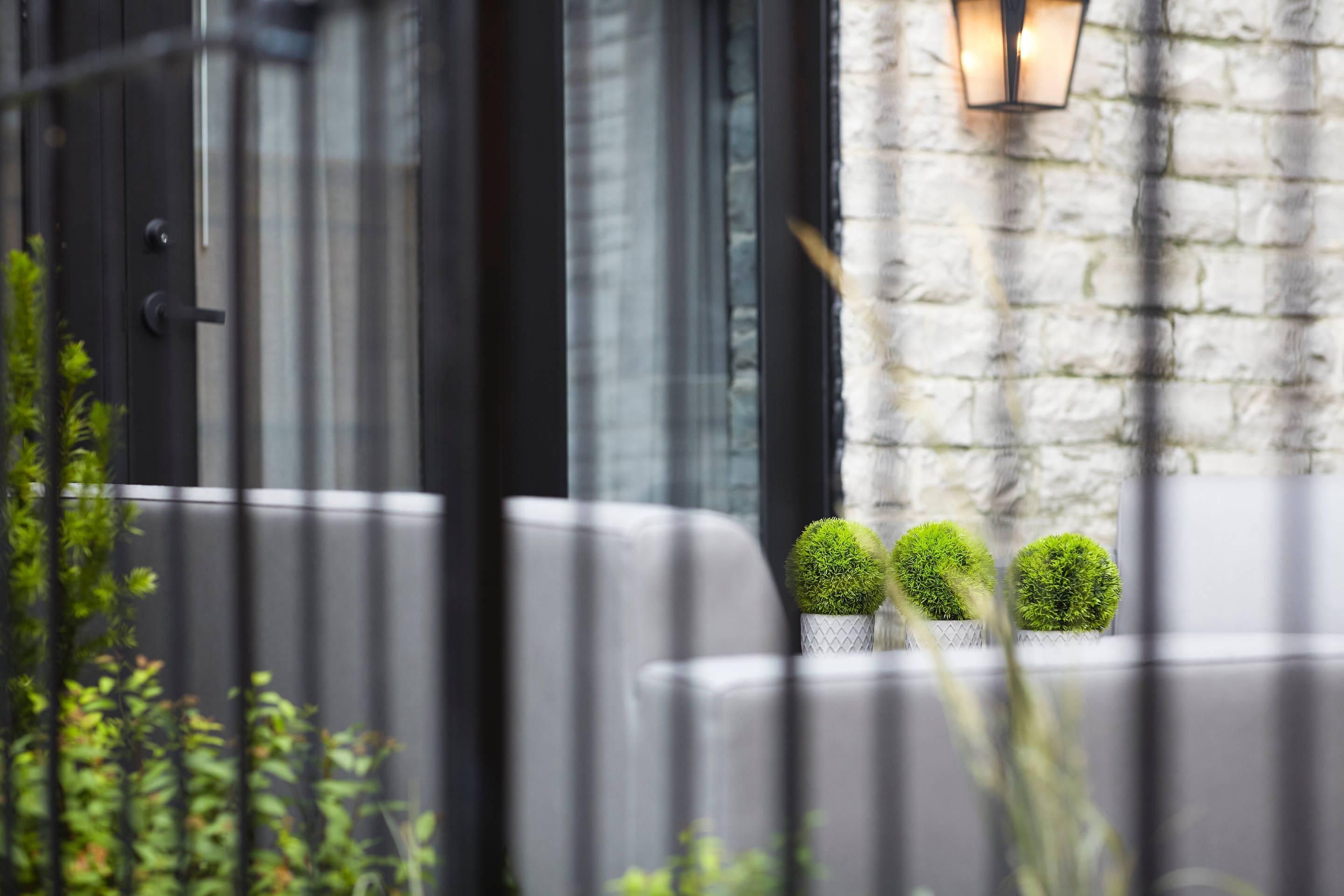 A modern building exterior with a stone wall, a black door, and a light fixture.