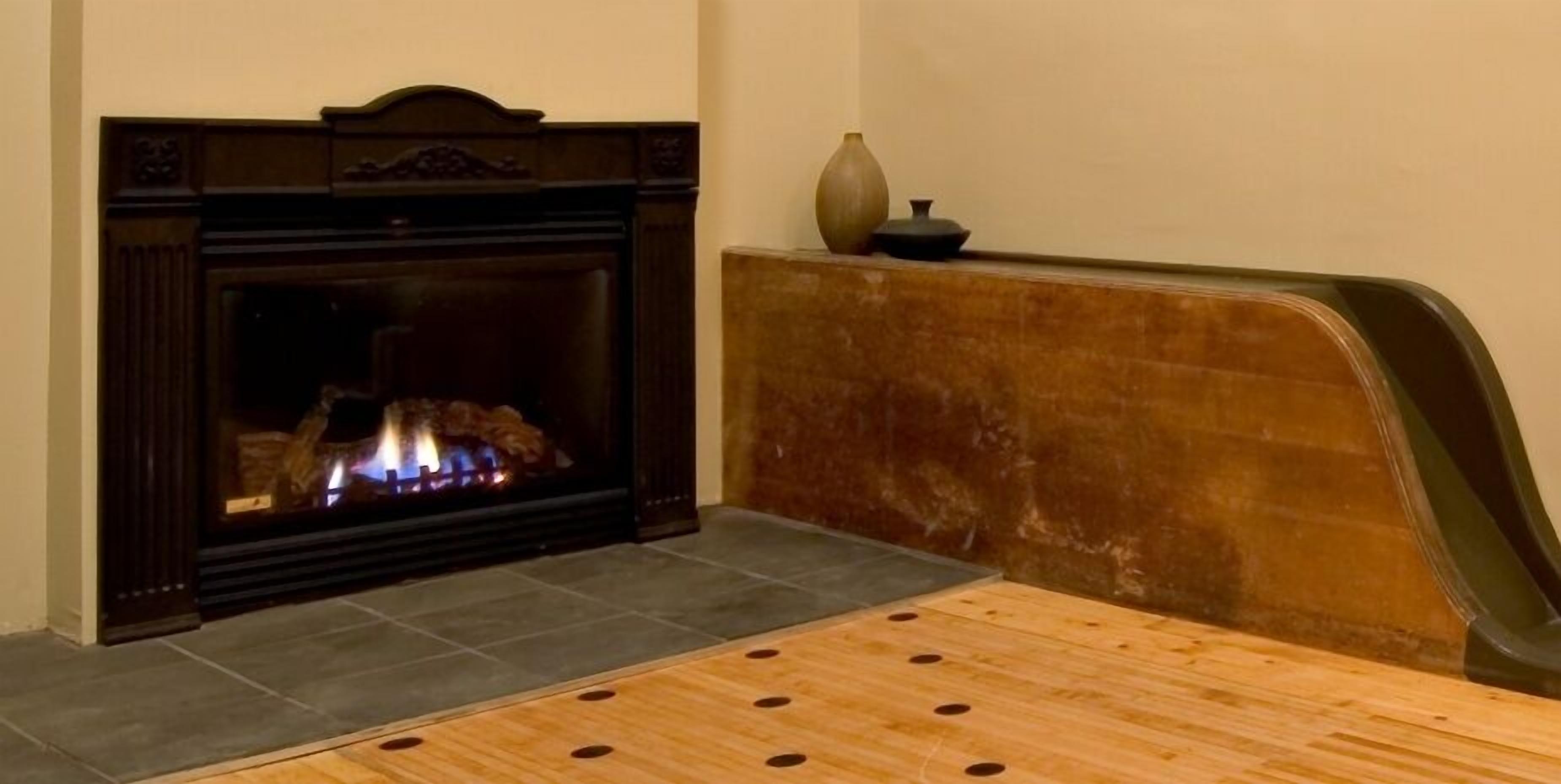A room with a fireplace, a wooden table, and a vase on a shelf.