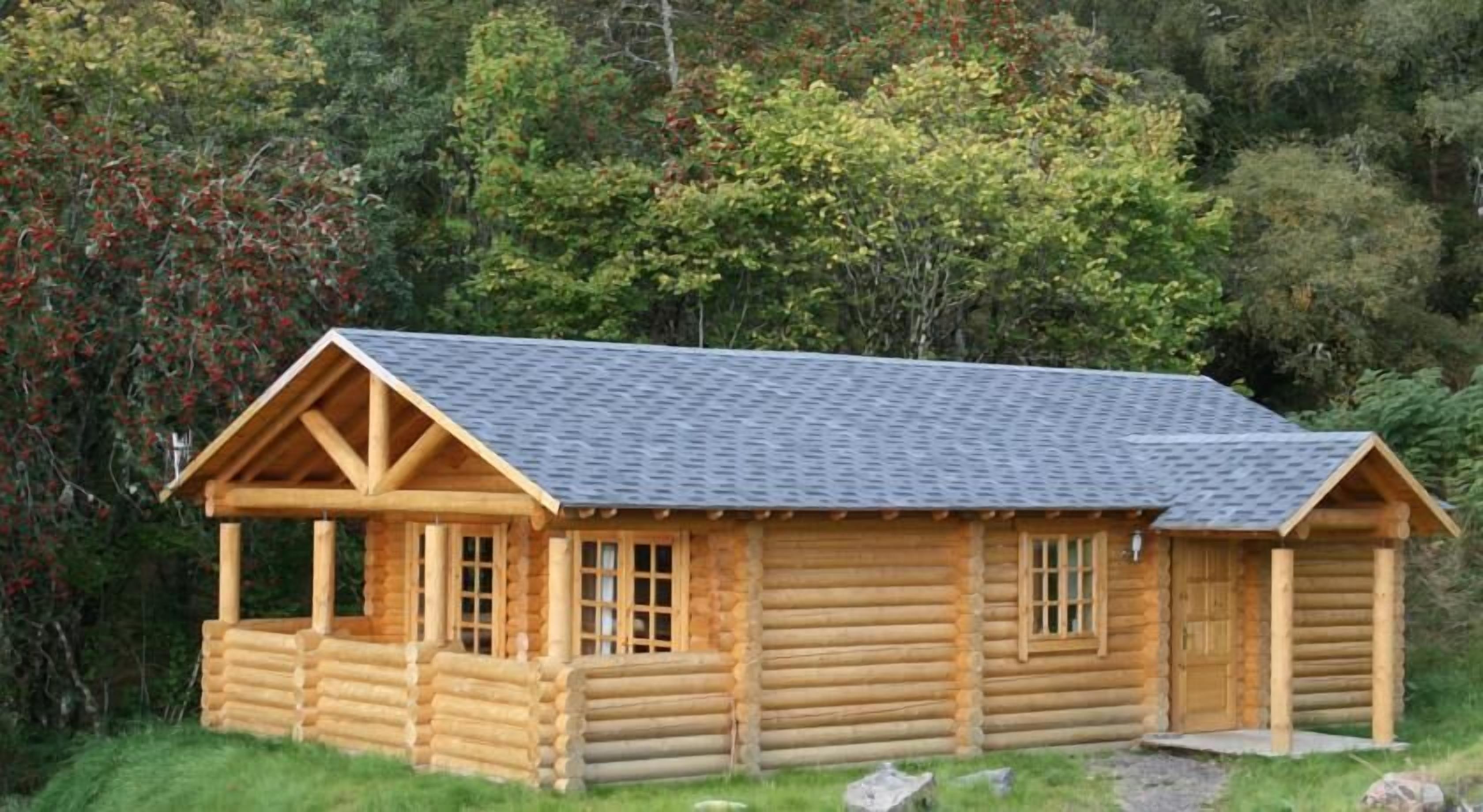 Una cabaña de madera con techo inclinado, un porche y una puerta frontal con ventanas.