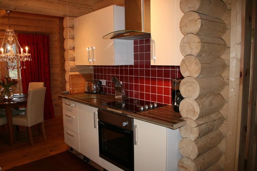 A kitchen with wooden log walls, a red-tiled backsplash, and a chandelier.