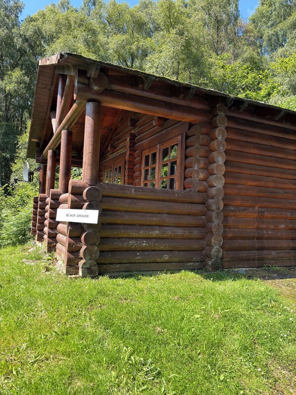 A log cabin with a porch, labeled 'BLACK GROUSE.' - BCC Loch Ness Log Cabins (Inverness)