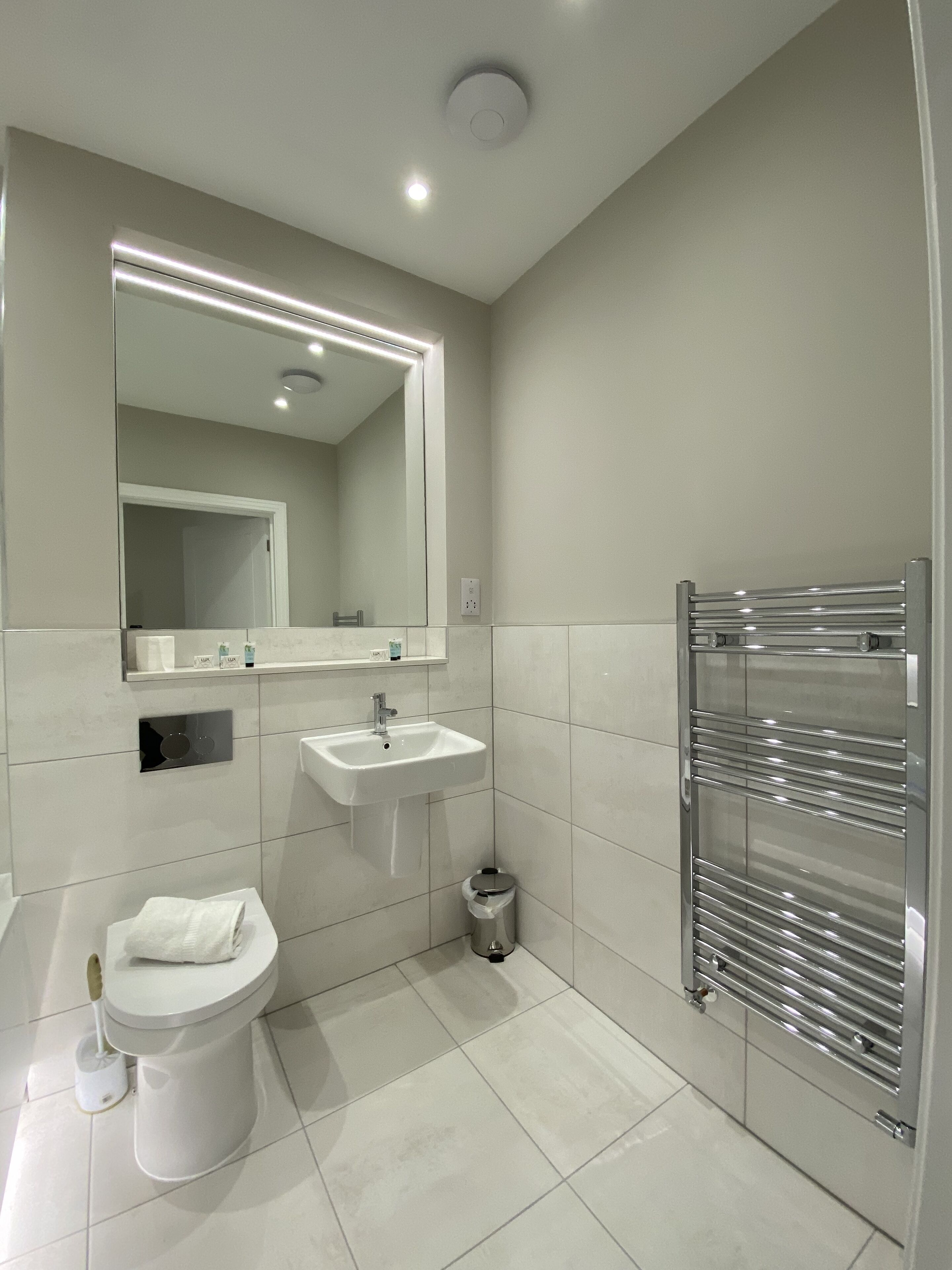 A modern bathroom with a toilet, sink, and mirror.