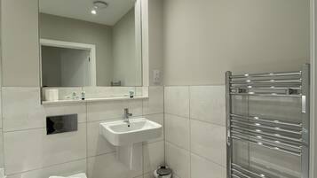A modern bathroom with a toilet, sink, and mirror.
