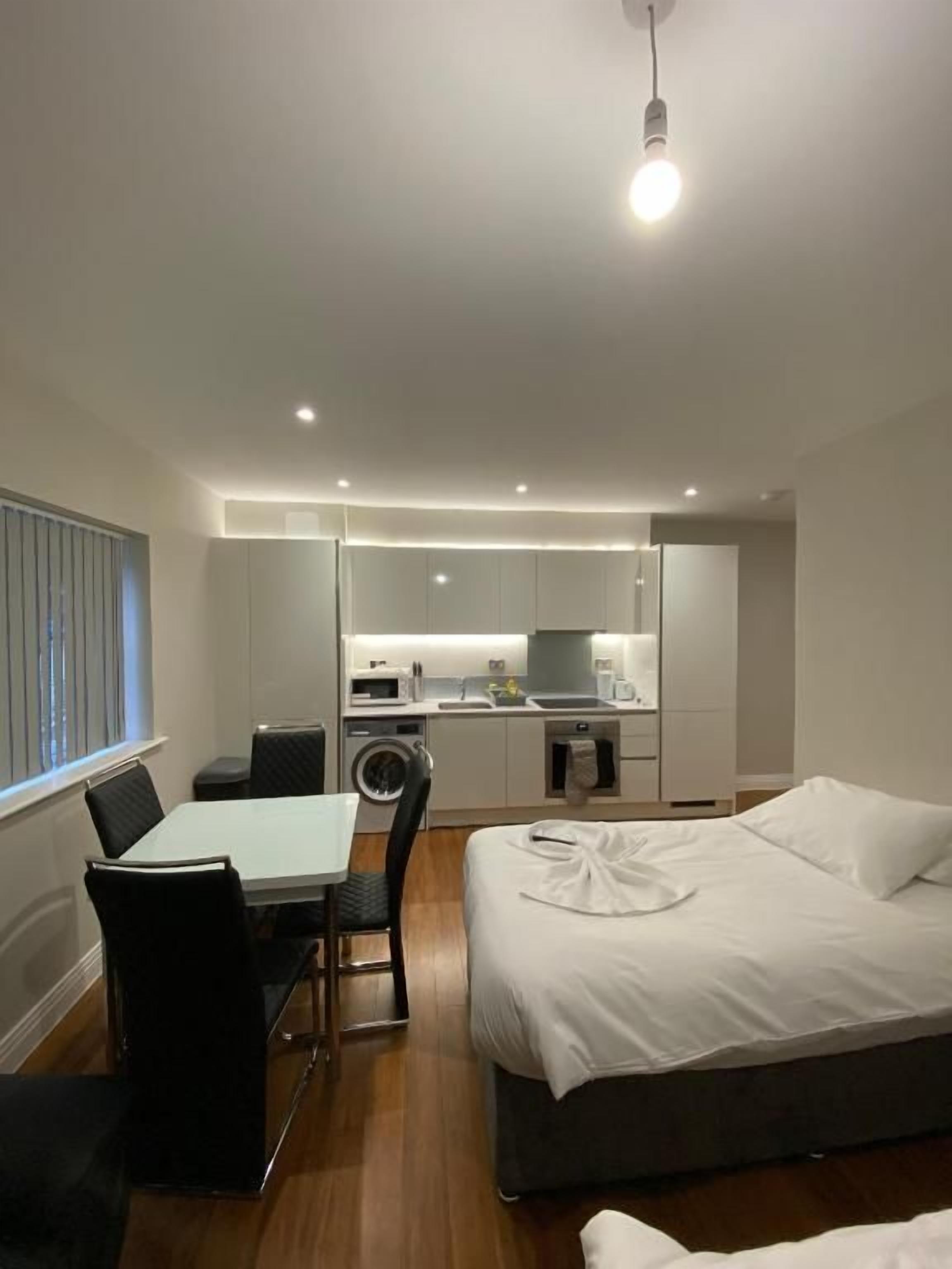 Ein modernes Hotelzimmer mit Bett, Esstisch und Küchenzeile.