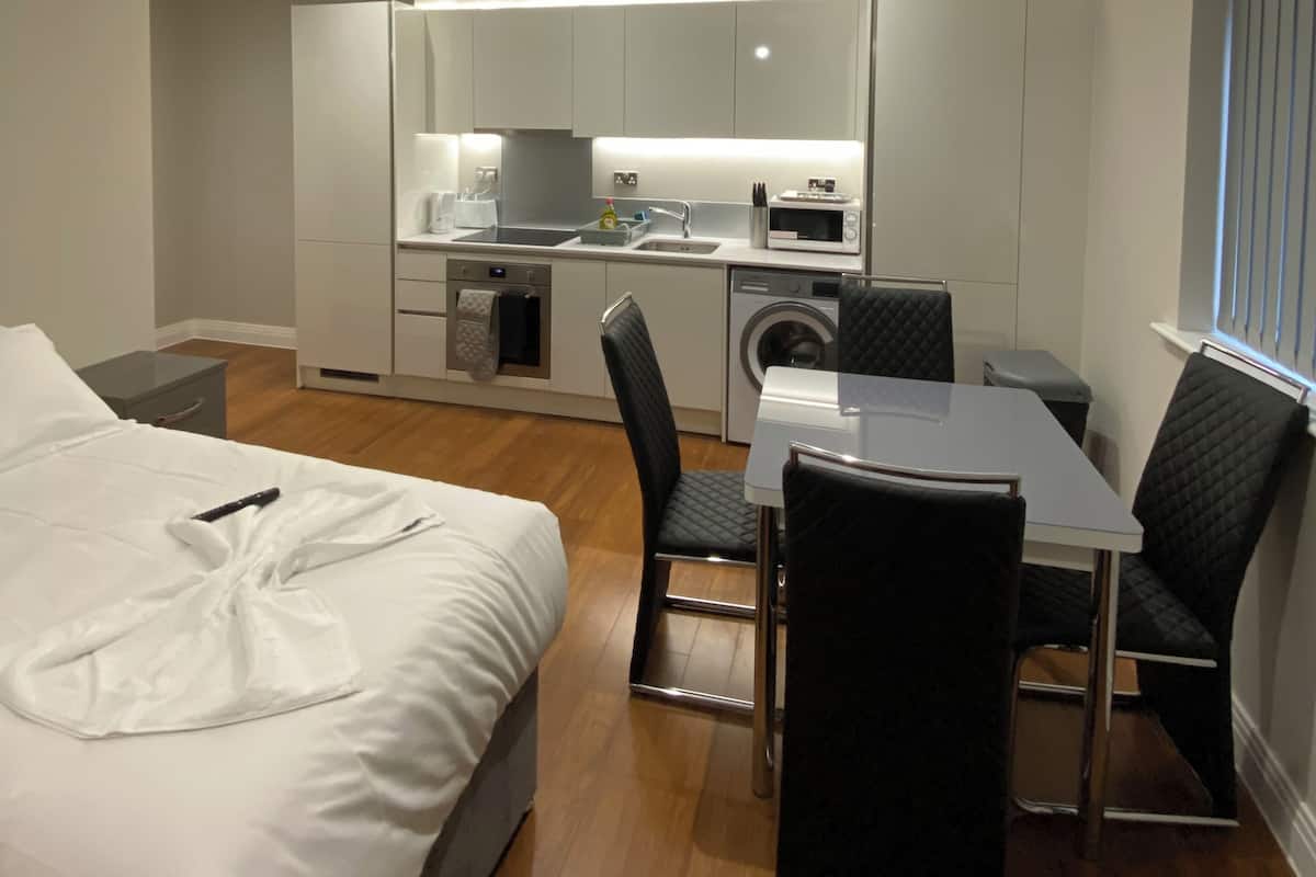Habitación de hotel compacta con cama, mesa de comedor y kitchenette.