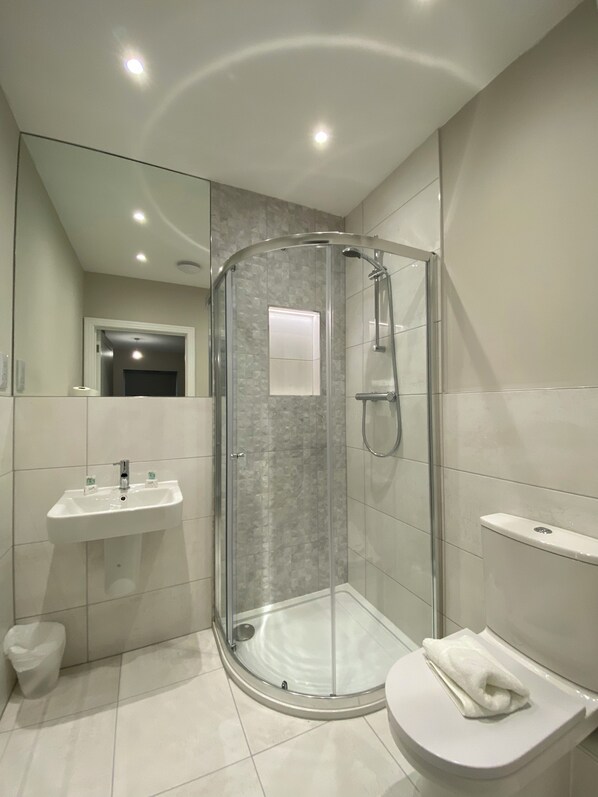 Un baño moderno con ducha de vidrio, lavamanos y retrete.
