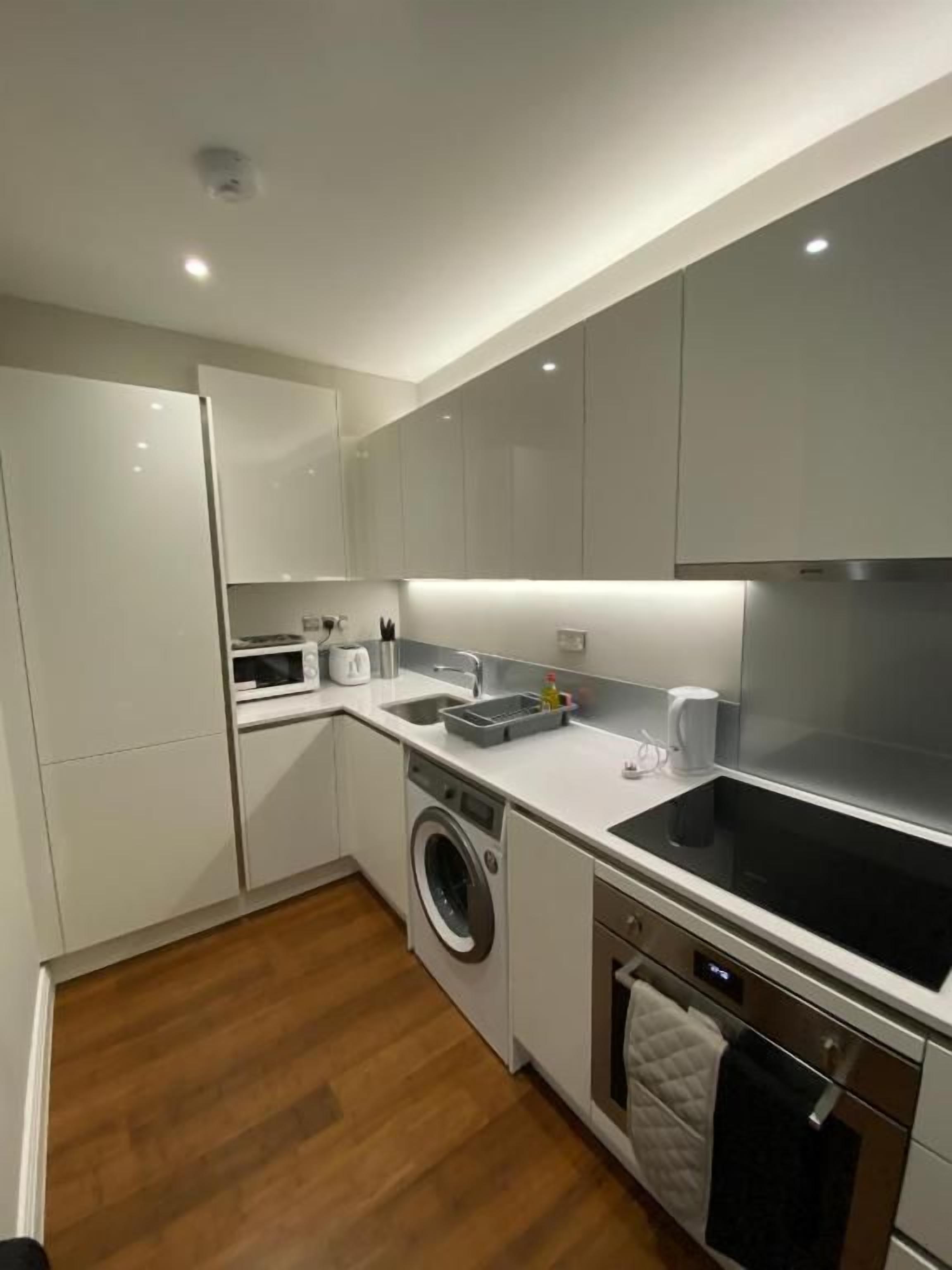 A modern kitchen with built-in appliances, a washing machine, and a digital oven.