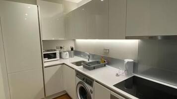 A modern kitchen with built-in appliances, a washing machine, and a digital oven.
