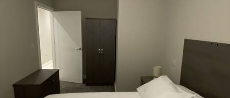 A hotel room with a bed, a dresser, a mirror, and a door.