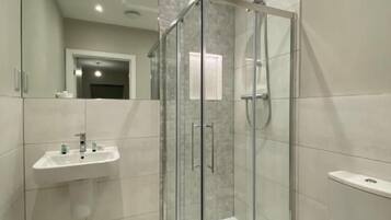 A modern bathroom with a glass-enclosed shower, a sink, and a toilet.