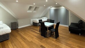 A modern loft bedroom with a dining area, wooden flooring, and a skylight. - Buckingham Apartments (High Wycombe)