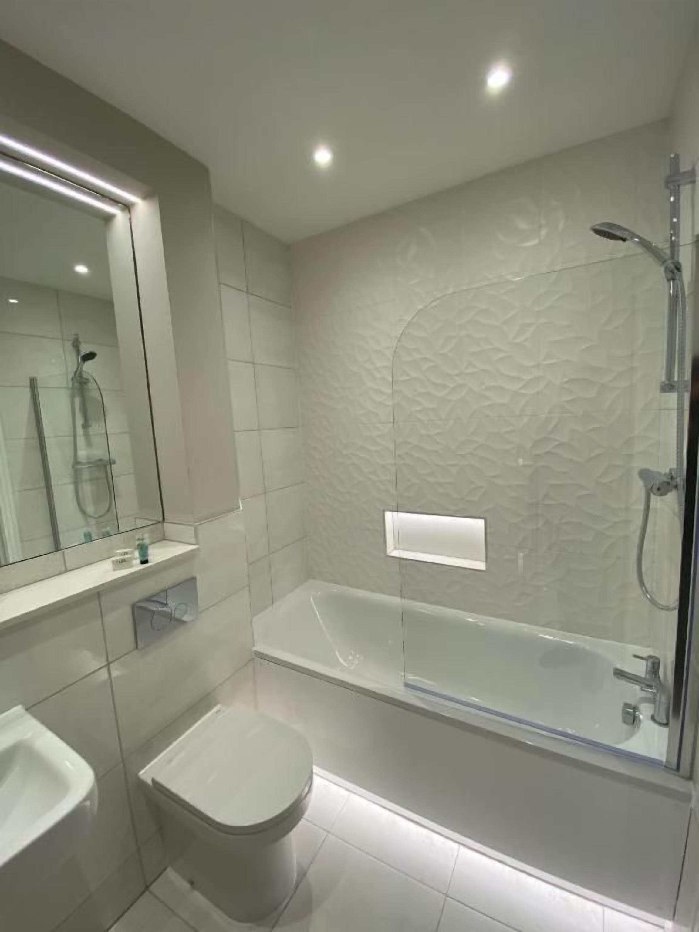 Un baño moderno con ducha envuelta en vidrio, inodoro y lavamanos.