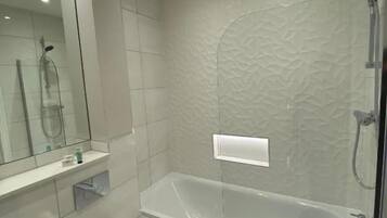 Un baño moderno con ducha envuelta en vidrio, inodoro y lavamanos.