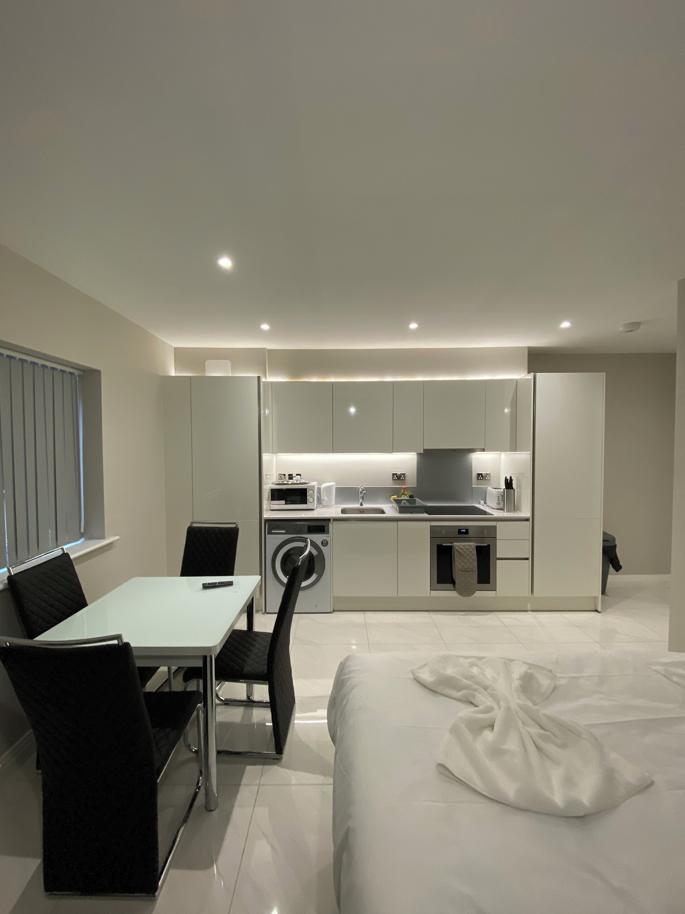 Una habitación de hotel moderna con zona de comedor, kitchenette y cama.