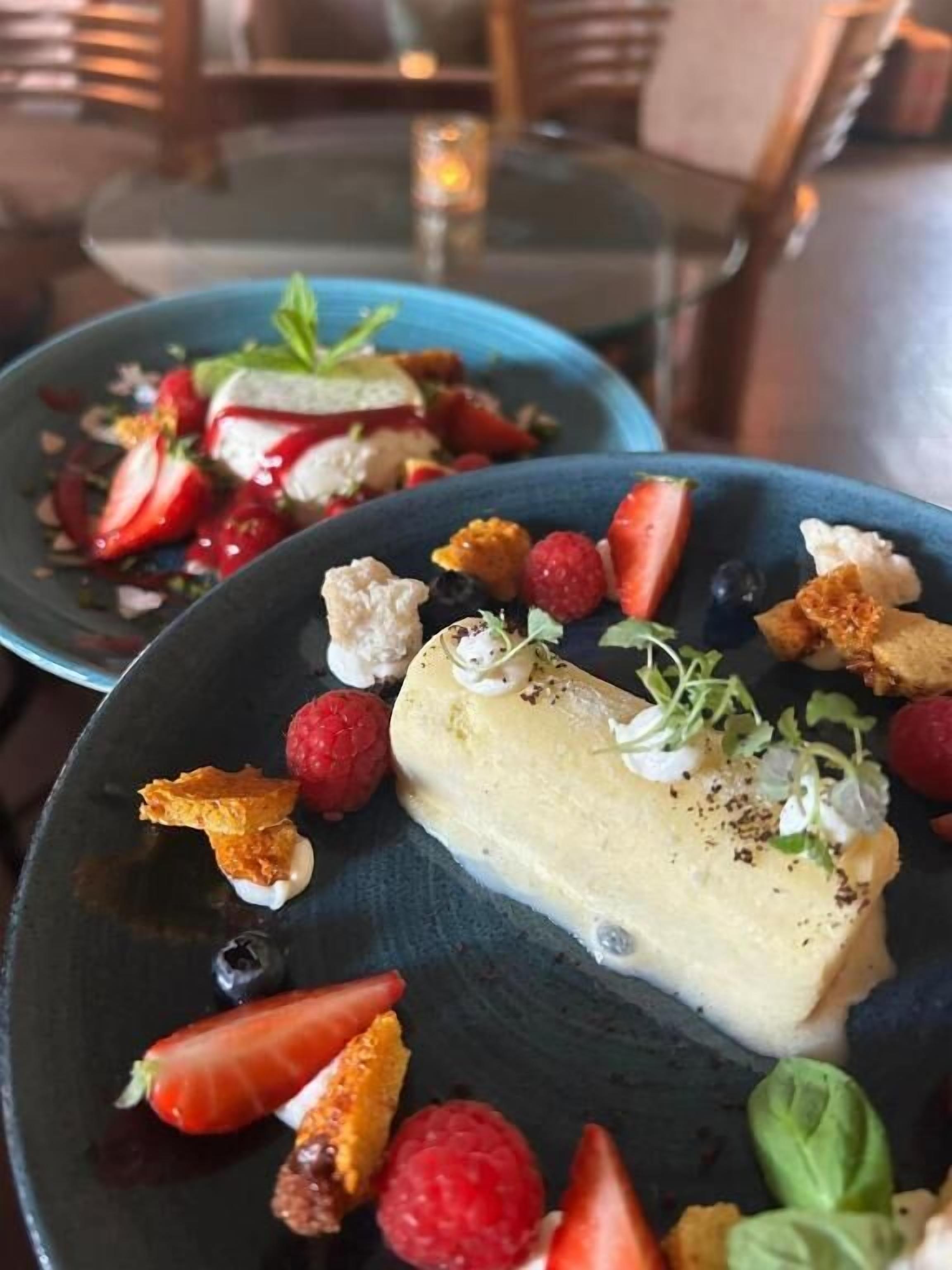 A dessert plate with a creamy dessert, strawberries, raspberries, and a blue plate.