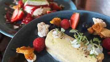 A dessert plate with a creamy dessert, strawberries, raspberries, and a blue plate.
