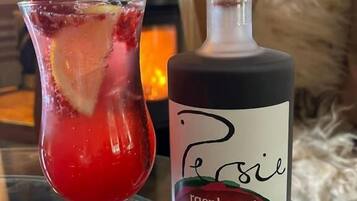 Un verre d’une boisson rouge, muni d’une paille, et une bouteille de gin à la framboise et à la menthe, posés sur une table.