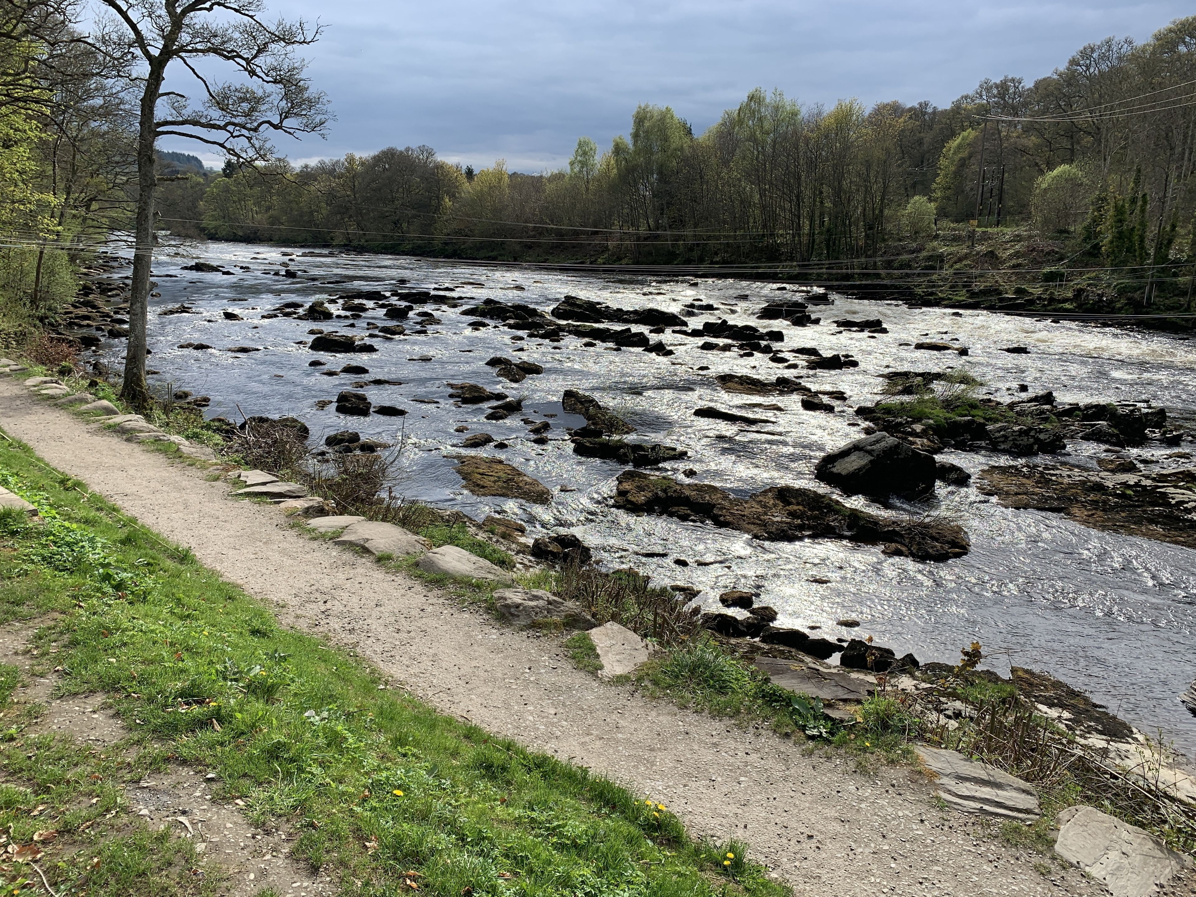 A river with rocks and a path alongside it.