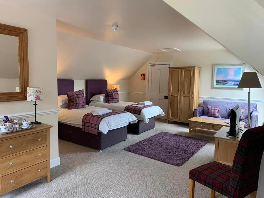 Une chambre avec deux lits, une commode, un bureau, une chaise et une armoire.